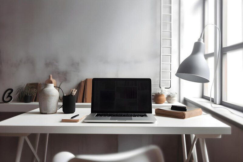 A white desk with a laptop and a lamp on top, creating a clean and organized workspace.